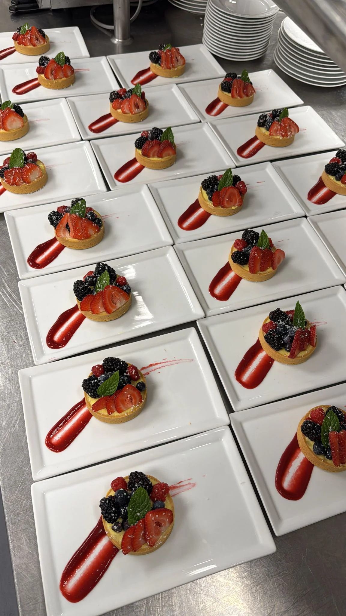 Berry Tartelettes — vanilla cream tarts with seasonal berries and raspberry coulis, lined for banquet service